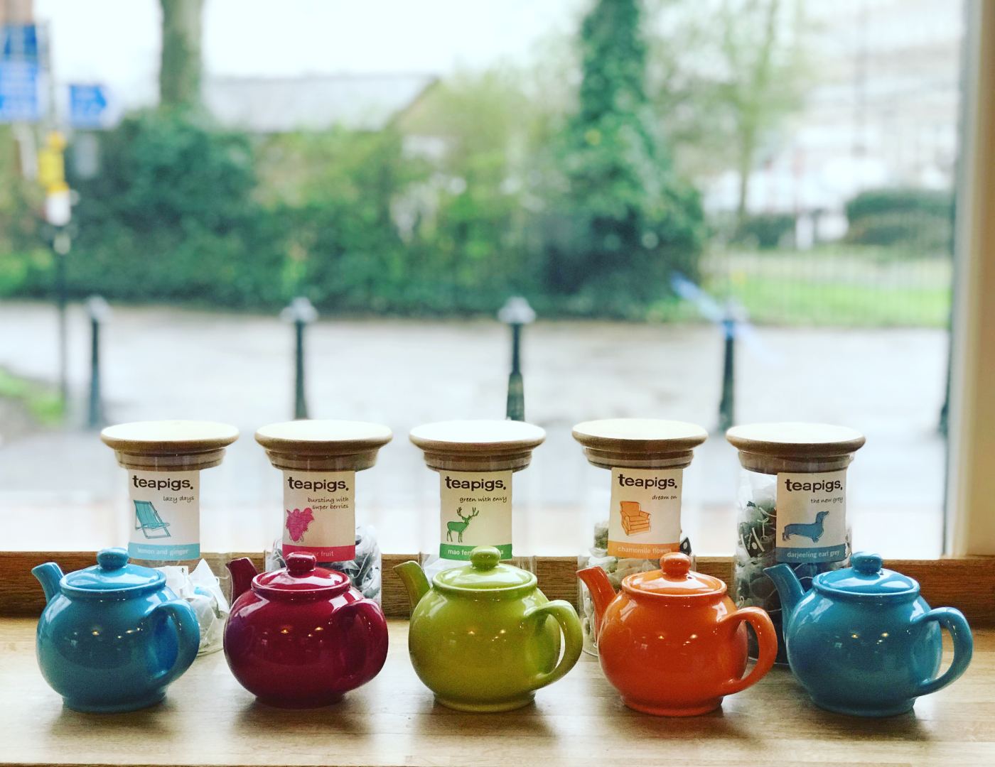 Colourful teapots lined up by the window at stop. coffee